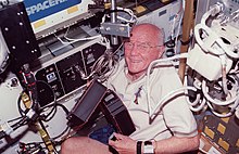 A bespectacled, smiling Glenn in close quarters on the space shuttle Discovery