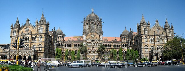 A brown building with clock towers, domes and pyramidal tops. Also a busiest railway station in India.[329] A wide street in front of it