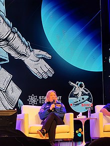 Fotografía de la Comandante Susan Kilrain en el campamento espacial Space 2101 en la Universidad de Ciencia y Tecnología Rey Abdalá en 2023. Hablando en un auditorio, sosteniendo un micrófono.