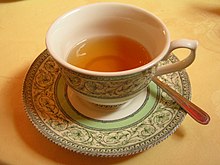 A filled cup of tea in a porcelain cup with a repeated floral pattern.