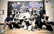 A group of eleven young men holding a large sign that says "BBoy Crew Battle Champion" while posing for a picture in front of a banner that says "Freestyle Session Taiwan".