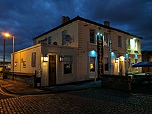 Large ornate white painted building illuminated at night with a dark blue sky