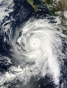 Satellite photograph of a sprawling, mature storm with a pronounced eye at the center and curving rainbands. The southern Baja California peninsula protrudes from the north.