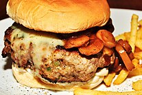 A cheeseburger with mushroom sauce and fries