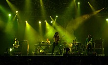 Several men performing onstage playing and singing into a microphone