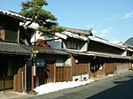 Two storied traditional Japanese houses next to a street.