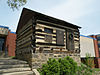 A rectangular log building with a stone foundation