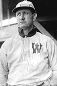 A man, wearing a baseball cap and a white baseball uniform with the letter "W" on the left breast, faces forward towards the left.