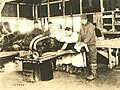 With the table rotated to its horizontal orientation and supported by a drum on one side and folding cot-like legs on the other, a veterinarian operates on a horse.