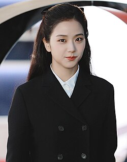 Jisoo looking towards the camera in a black coat