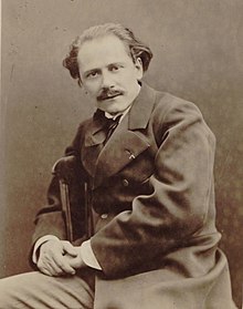 Middle-aged man, receding hair, neatly moustached, looking at camera