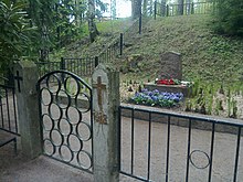 A modest tombstone, with flowers in front of it and an iron fence surrounding it, is the grave site for Red soldiers in civilians in Helsinki.