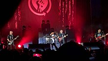 Rise Against performing on stage. Four band members can be seen.