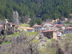 Colour photograph of a sparse cluster of red-roofed low buildings on a mountainside