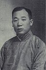 A black-and-white image of a man in a high-collared shirt looking forward