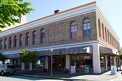 Photograph of a two-story building on a street corner with retail space at sidewalk level