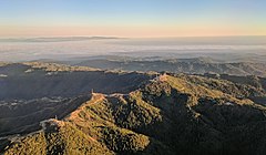 Loma Prieta (the peak just right of center) and other nearby peaks are festooned with television broadcast towers and other communication towers, serving the Santa Clara Valley. Fog-shrouded Monterey Bay and the Monterey peninsula are visible in the background in this late-afternoon approach to San José International Airport.