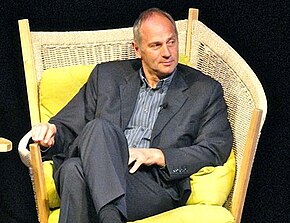 Steve Regrave in a black suit sitting in a wicker chair in 2012.