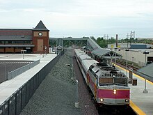 A train at a railway station with a modern platform and station building