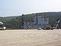 Profile view of this Yukon dredge tied up to a quay, note the size. The dredge conveys the spoils to the rear (left side) into a receiving vessel such as a barge.