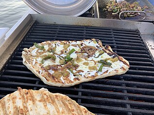 Pizza grilling on an outdoor gas range