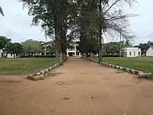 Long driveway leading to a white building