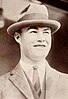 Black and white photograph of a young man wearing a 1920s vintage suit and tie with a trilby hat