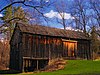 An unpainted wooden barn with a shingle roof in the sunlight