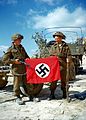 Canadian soldiers during Operation Overlord showing a captured Nazi flag as a war trophy outside Hautmesnil, France in August 1944. Photo: National Archives of Canada