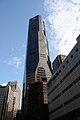 Ground-level view of 70-storey building. The exterior has a reddish hue with dark windows. The building tapers slightly at two points.