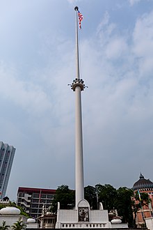 A tall white flagpole with the Malayan flag.