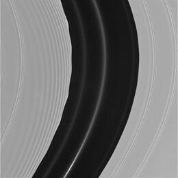 The motion of Pan (not visible) through the A ring's Encke Gap induces edge waves and a set of spiraling wakes (which are not self-propagating) ahead of it in its orbit on the gap's inner side. The other more tightly wound bands are spiral density waves.