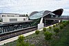 Picture of Tallawong station viewed from the outside. It consists of a curved roof covering a platform in a cutting below ground.