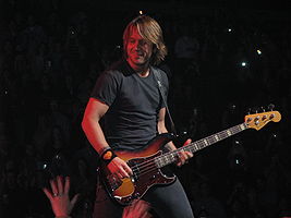 Urban holding a bass guitar onstage