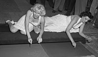 Marilyn Monroe and Jane Russell putting signatures, hand and foot prints in cement at Grauman's Chinese Theater, 1953