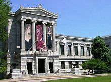 Gray stone classical building with columns and art banners on the central façade