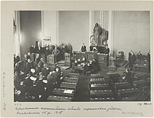 Parliament is convening for the first time after the war. Whites and German soldiers dominate the picture while only one person from the opposing social democrats is present. Thus, it was sarcastically called a Rump Parliament.