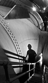 A worker stands by the 30 ft. diameter Nevada penstock before its junction with another penstock that delivers water to a turbine.