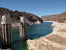 View of a reservoir where the water level has dropped, showing white deposits on the surrounding mountains