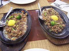 Sisig is a fried and sizzled chopped bits of pig’s head and liver. Other versions using tuna or milkfish, usually seasoned with calamansi and chili peppers and sometimes topped with an egg.