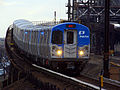 A gray and blue PATH train travels along an elevated track.