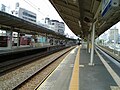 JR platforms at Motomachi; a freight train passes by in the background