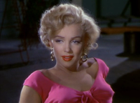 Monroe en Niagara. Un primer plano de su rostro y hombros; ella lleva aretes de oro y una blusa rosa impactante.