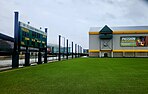 Photo showing a field and scoreboard, with a building in the background.