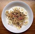 Muesli (traditionally raw rolled oats, dried fruits and nuts), shown with milk and banana. Contrast with granola, which is baked.