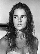 Black-and-white publicity photograph of a Caucasian woman. The woman has blonde wavy hair and is wearing a silk dress.