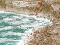 A rough Dead Sea, with salt deposits on cliffs