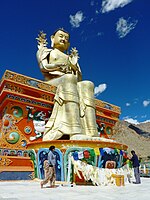 Hanging prayer flags on the 23 m (75 ft) statue of Maitreya