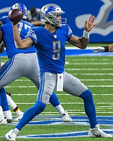 Matthew Stafford throwing a pass in a Detroit Lions uniform.