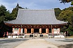 Wooden building with hip-and-gable roof, white walls, vermillionred beams and an open veranda.